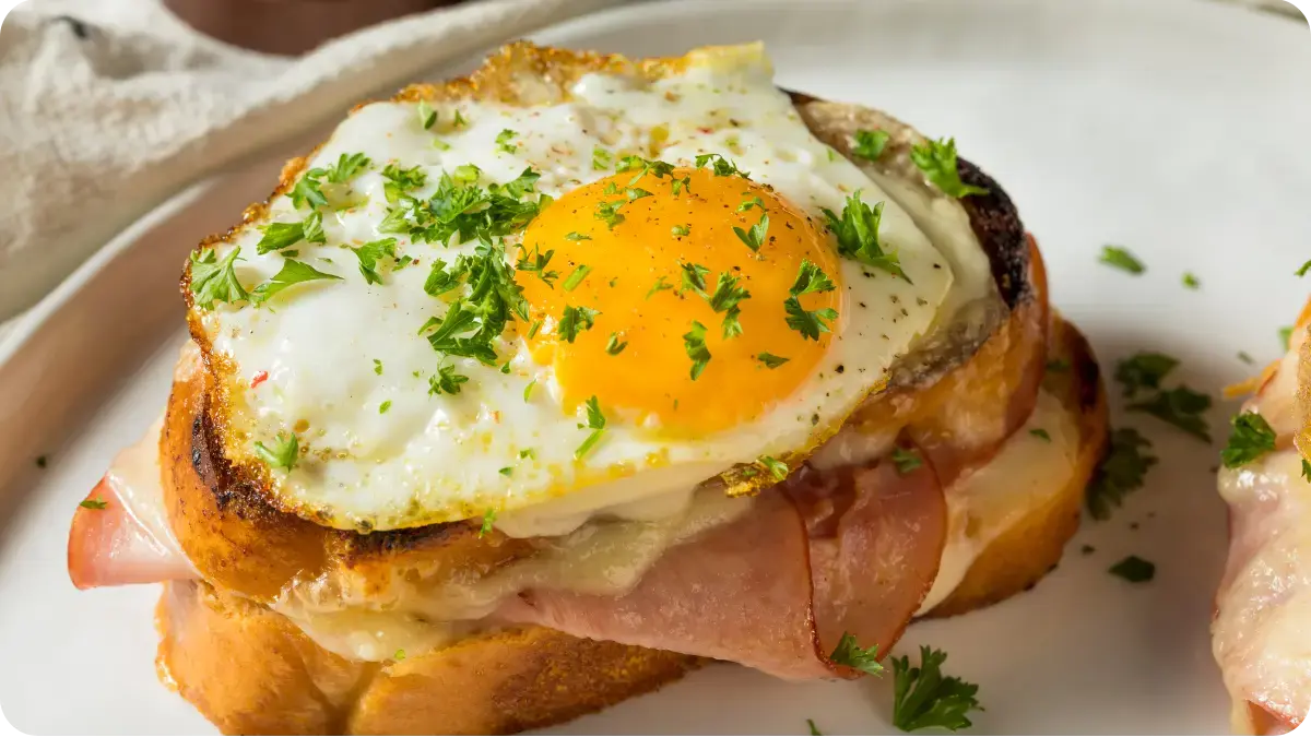 A fried egg on top of a ham and cheese toastie. A fried egg on top of a ham and cheese toastie.