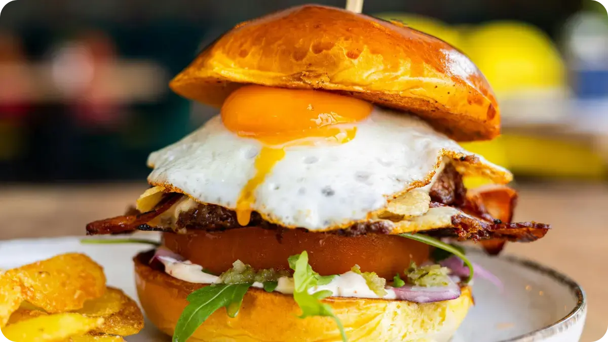 A beef burger topped with a fried egg, in a bun. A beef burger topped with a fried egg, in a bun.