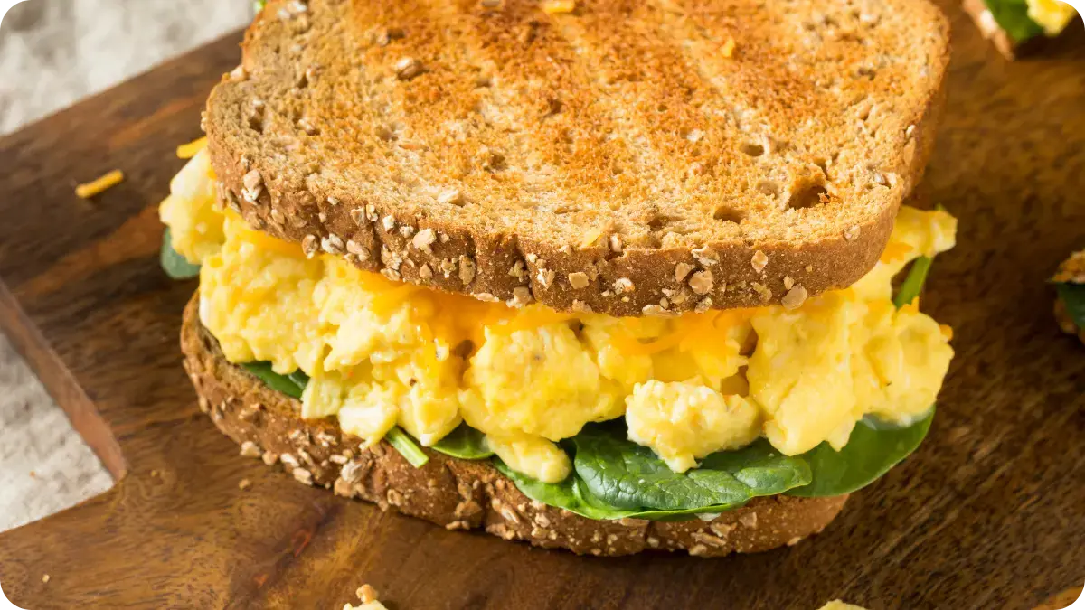 Scrambled egg on a bed of rocket inside a toasted sandwich.