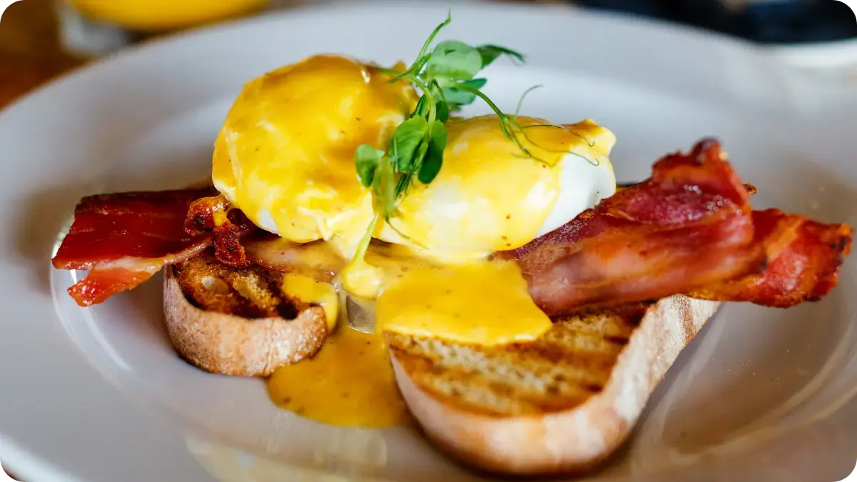 Poached eggs and bacon covered in Hollandaise sauce on top of toast. Poached eggs and bacon covered in Hollandaise sauce on top of toast.